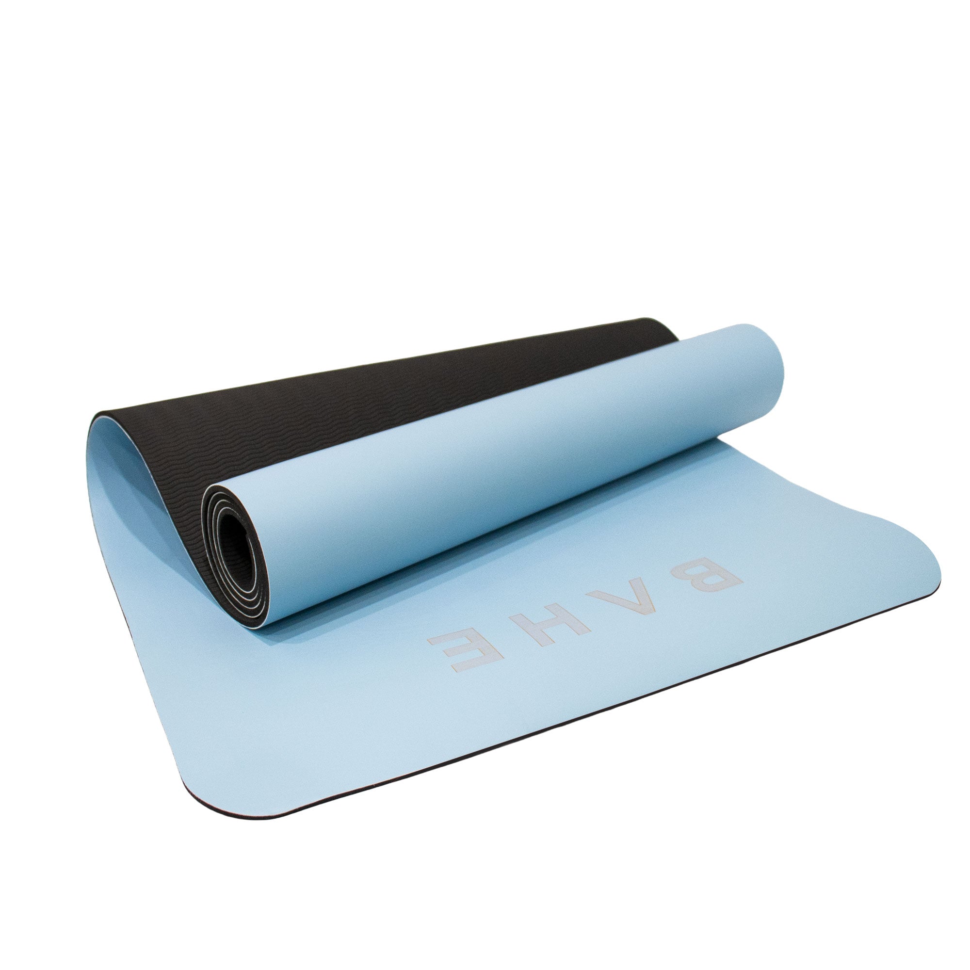 A light blue yoga mat with a black textured underside, partially unrolled to show the brand name 'BAHE' printed in light pink on the top surface, set against a plain white background.