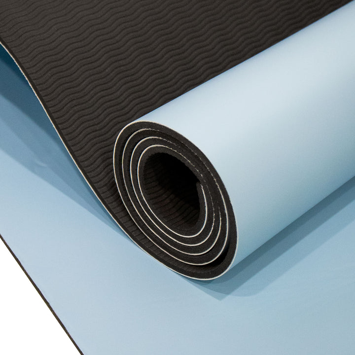 A rolled exercise or yoga mat shown close up, with a black textured top surface and a light blue underside.