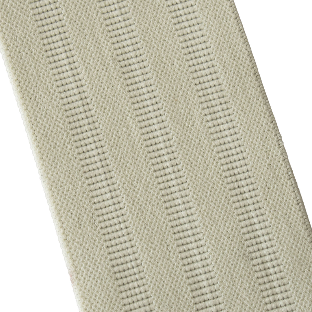 A close-up of a woven fabric strap or trim in a light beige color, showing a textured diagonal weave pattern against a white background.