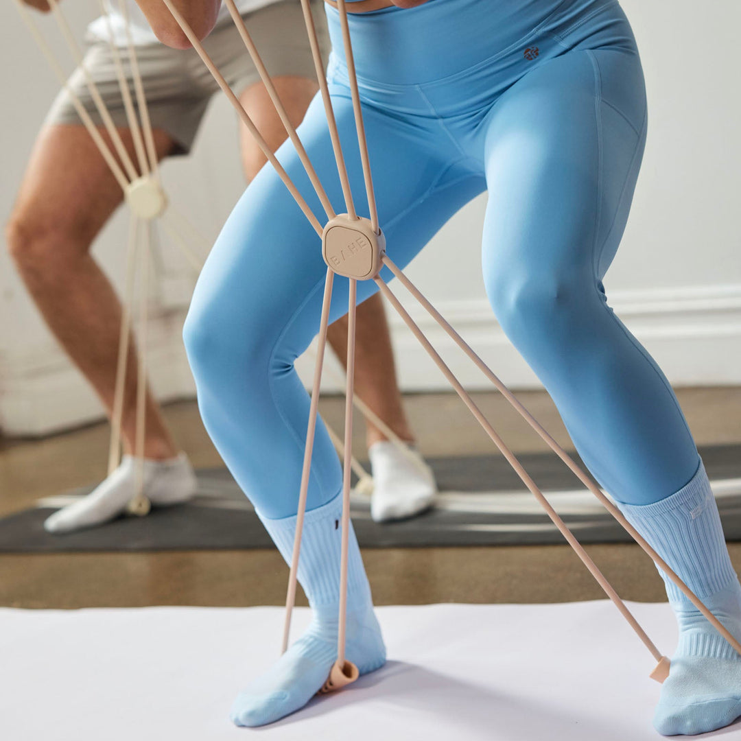 A close-up lifestyle shot of a person in using pilates socks and using a flow reformer which mimics the movement of a reformer bed without the need for a reformer carriage