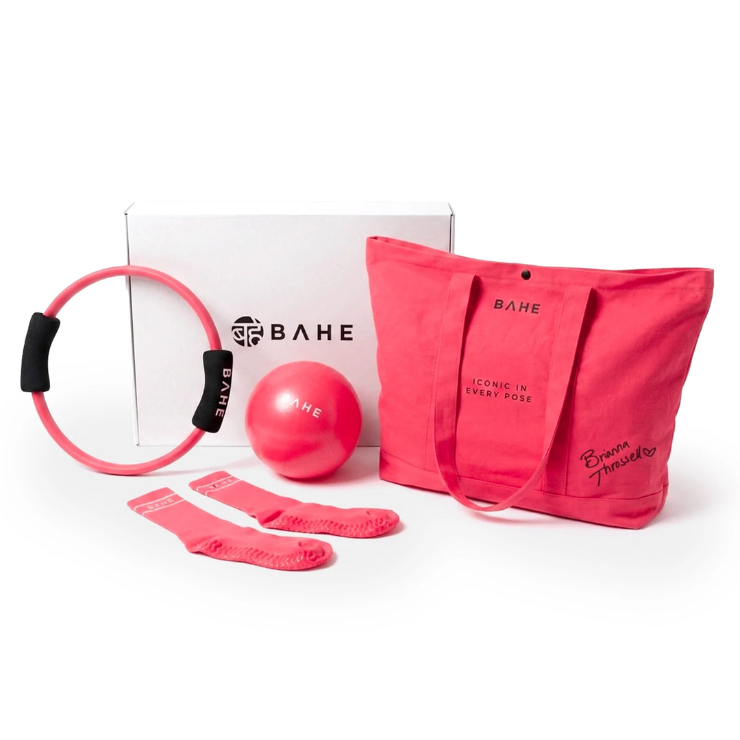 A pink fitness and gym accessory set from BAHE, including a pink resistance ring with black handles, a pink exercise ball, a pair of pink socks, and a pink tote bag, arranged in front of their white branded packaging box on a white background.