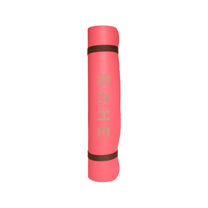 Pink yoga mat with brown accents on a white background