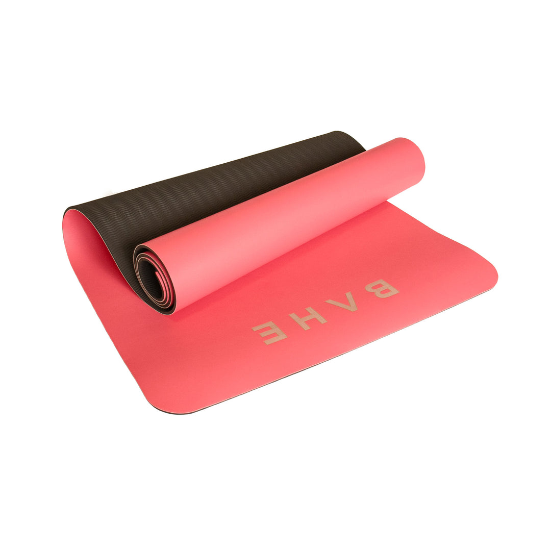 Pink yoga mat with black rolled-up end on a white background